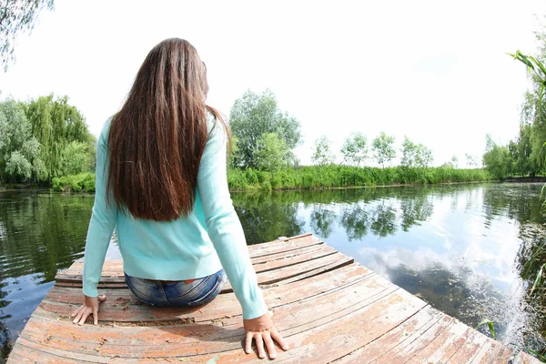 Žena sedí na dřevěném molu — Stock fotografie