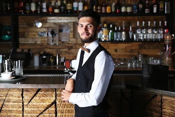 Waiter standing near wooden bar counter