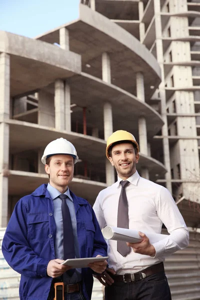 Schöner Ingenieur Und Arbeiter Mit Tablet Computer Vor Unvollendetem Gebäude — Stockfoto