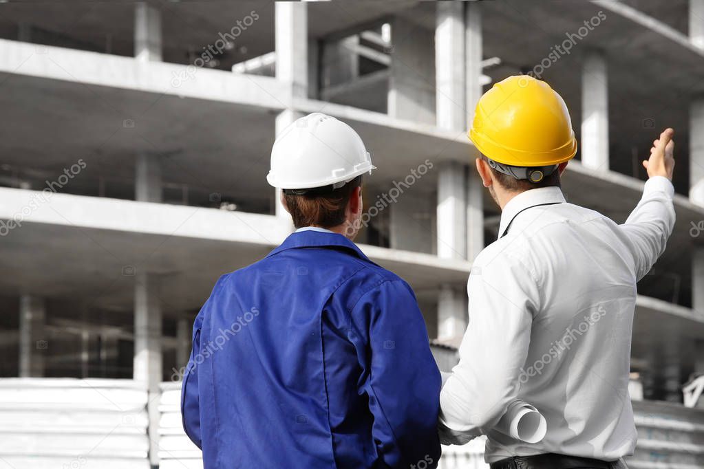 Engineer and worker discussing construction of unfinished building