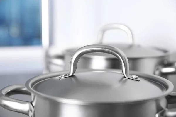 Stainless saucepans on kitchen table — Stock Photo, Image