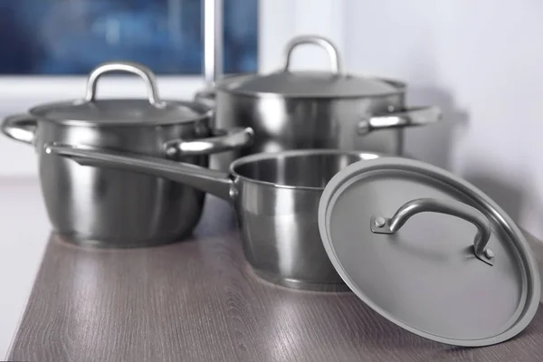 Stainless saucepans on kitchen table — Stock Photo, Image