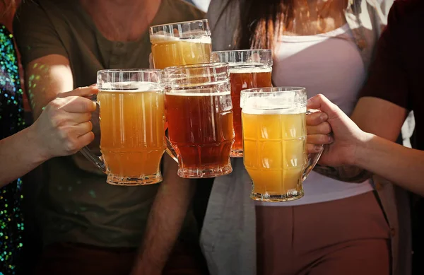 People clinking mugs with beer — Stock Photo, Image