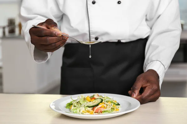 Cuoco afroamericano che cucina gustosa insalata in cucina, primo piano — Foto Stock