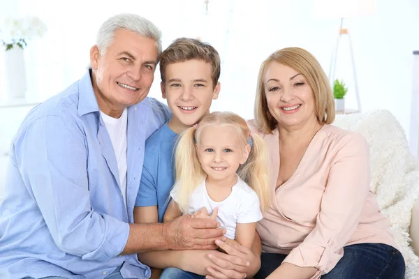 Niedliche Kinder mit Großeltern sitzen auf Sofa im Wohnzimmer — Stockfoto