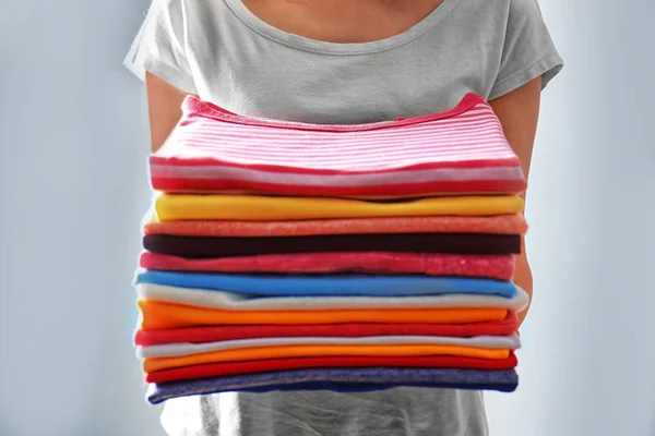 Woman holding stack of clothes — Stock Photo, Image
