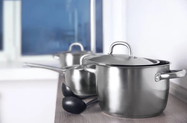 Stainless saucepans on kitchen table — Stock Photo, Image