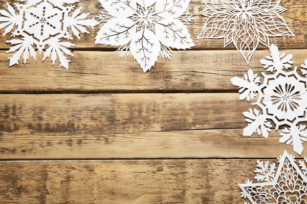 Belos flocos de neve de papel no fundo de madeira — Fotografia de Stock