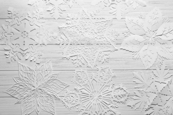 Schöne Papierschneeflocken auf hellem Holzhintergrund — Stockfoto