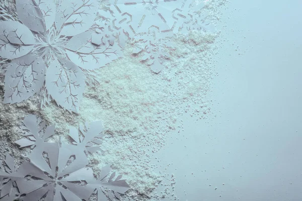 Красиві паперові сніжинки та сніг на білому тлі — стокове фото