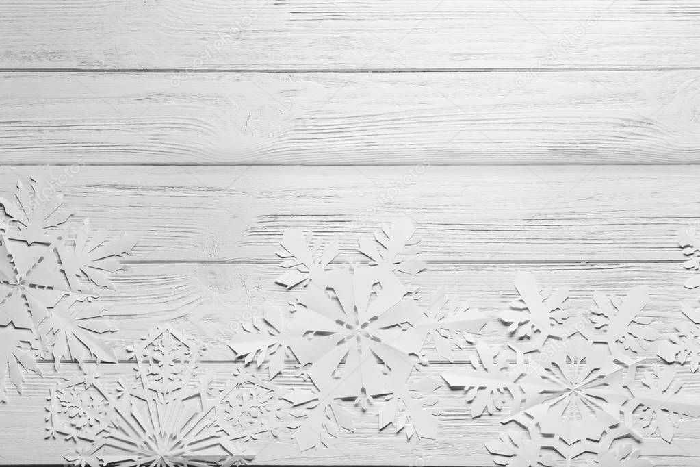 Beautiful paper snowflakes on light wooden background