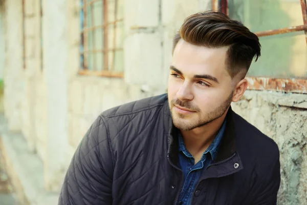 Handsome man in jacket on grunge building background