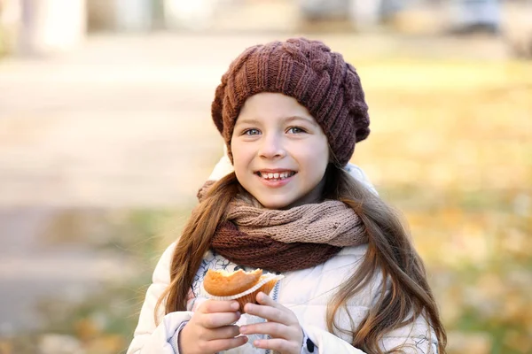 Cute little girl eating tasty muffin — Stock Photo, Image