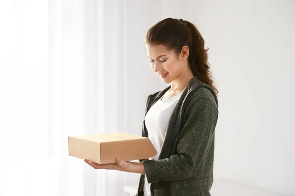 Beautiful young woman with parcel at home