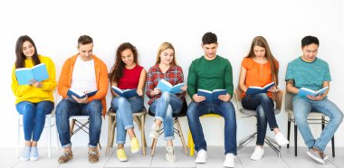 Bir grup insan ışık duvarının yakınında otururken kitap okuma