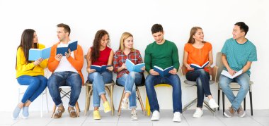 Bir grup insan ışık duvarının yakınında otururken kitap okuma