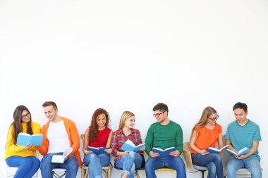 Bir grup insan ışık duvarının yakınında otururken kitap okuma