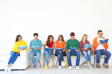 Bir grup insan ışık duvarının yakınında otururken kitap okuma