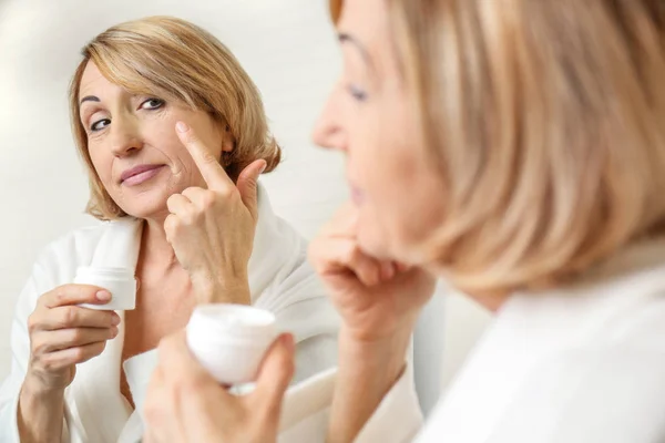 Donna anziana che applica la crema — Foto Stock