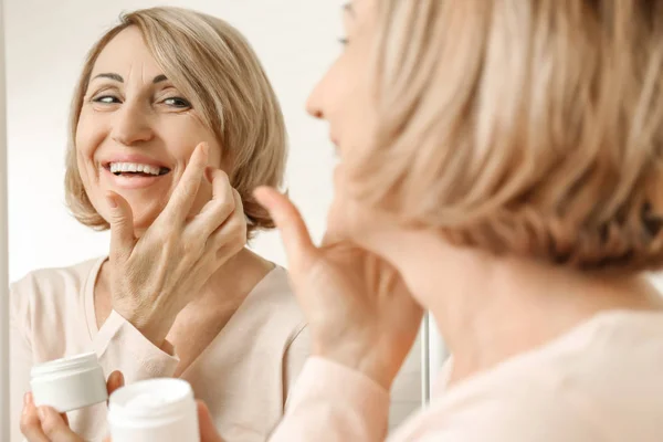 Femme âgée appliquant de la crème — Photo