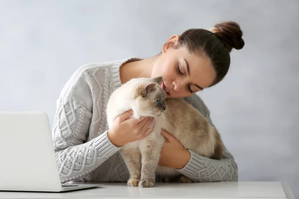 Mulher sentada à mesa com gato bonito — Fotografia de Stock