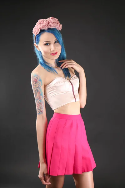 Gyönyörű fiatal nő, elegáns színű haja és sötét háttér tetoválás — Stock Fotó
