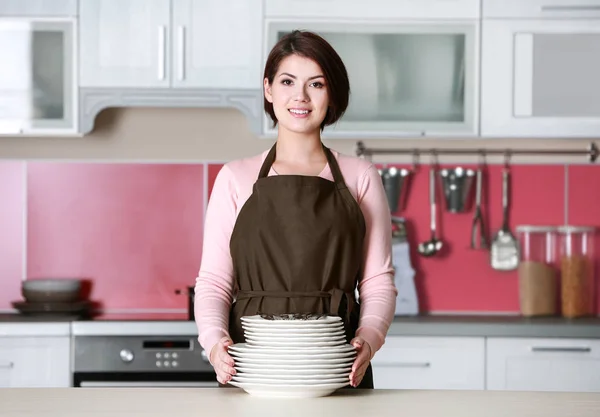 Молодая женщина с кучей посуды — стоковое фото