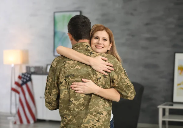 Soldat in Tarnkleidung umarmt seine Frau zu Hause — Stockfoto