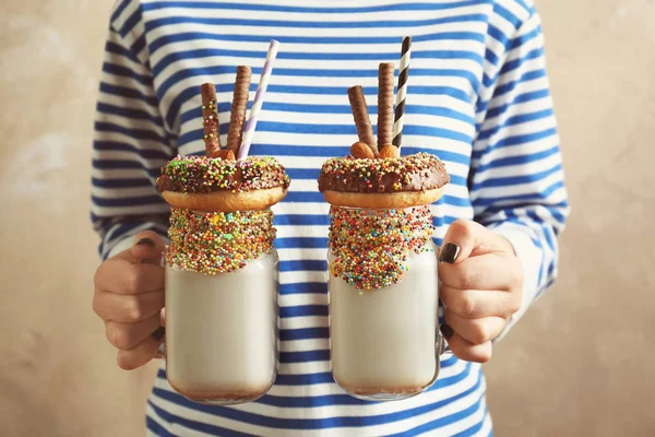 Girl holding milkshakes with donuts