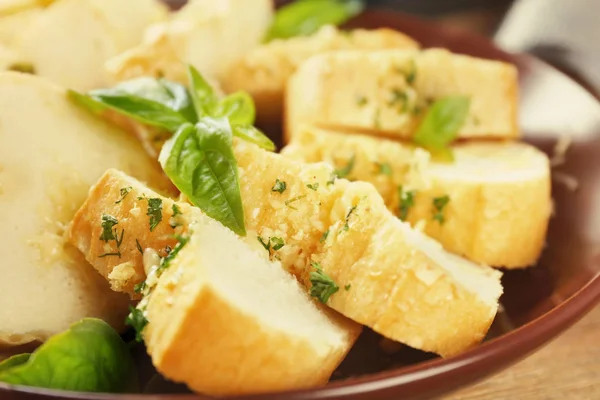 Rebanadas de sabroso pan con ajo y hierbas en el plato — Foto de Stock