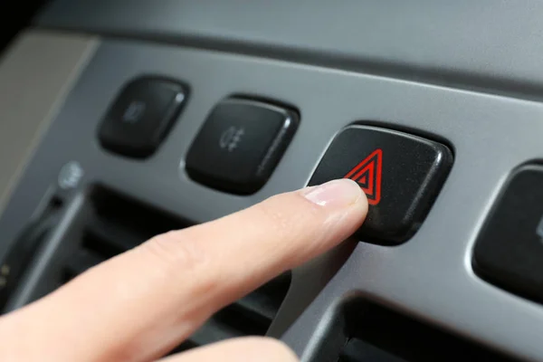 hand pressing emergency warning button on car