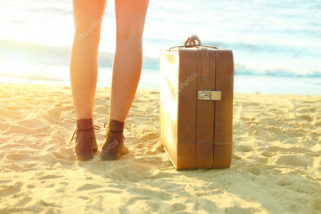 Young woman with suitcase standing 