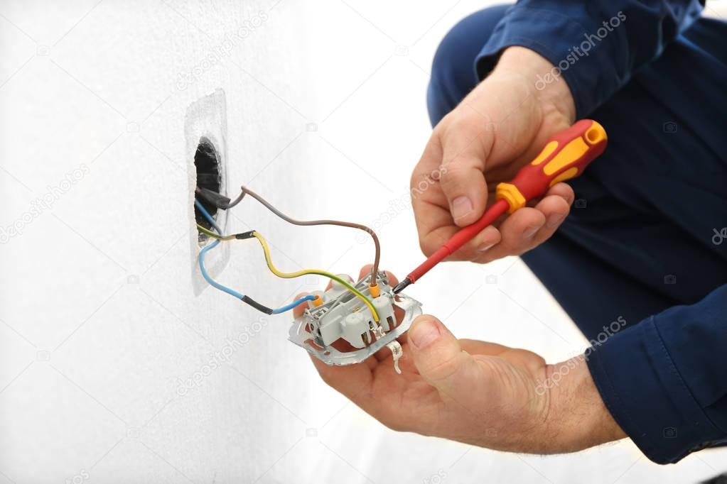 Electrician disassembling wall socket  