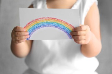 Child holding drawing of colorful rainbow clipart