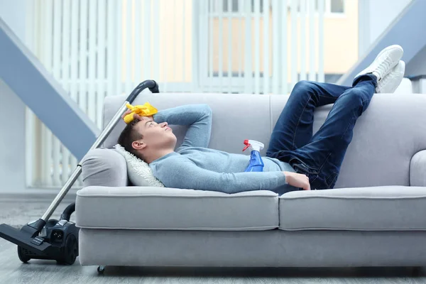 Väsynyt mies makaa sohvalla — kuvapankkivalokuva
