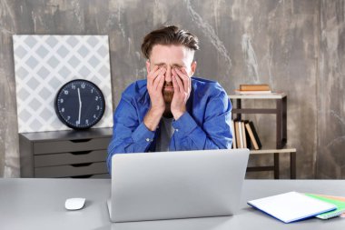 Genç adam dizüstü bilgisayar ile yorgun 