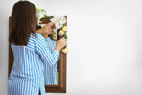 Vrouw versieren spiegel met bloemen — Stockfoto