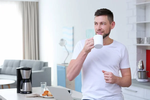 Beau jeune homme buvant du café à la maison — Photo