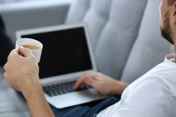 Laptop ile evde çalışırken içme kahve genç adam — Stok fotoğraf