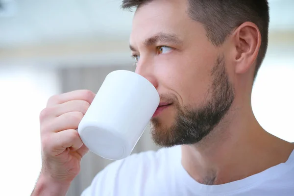 Knappe jonge man drinken koffie thuis, close-up — Stockfoto