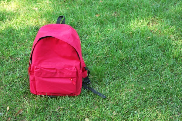 Red backpack on grass — Stock Photo, Image