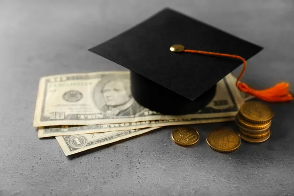 Sombrero de graduación, billetes de dólar y monedas en la mesa. Concepto de bolsillo dinero — Foto de Stock