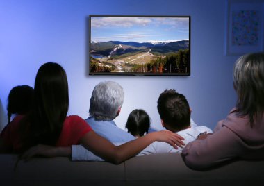 Evde televizyon izleyen bir aile. 