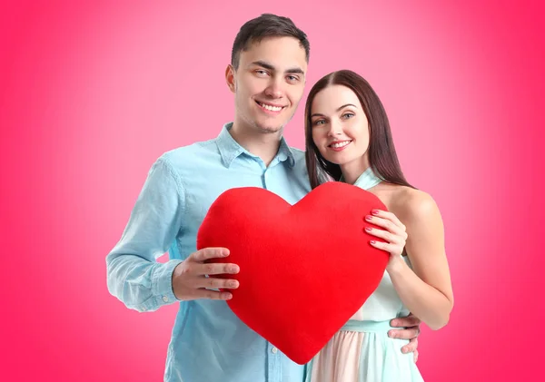 Casal jovem com coração posando no fundo de cor — Fotografia de Stock