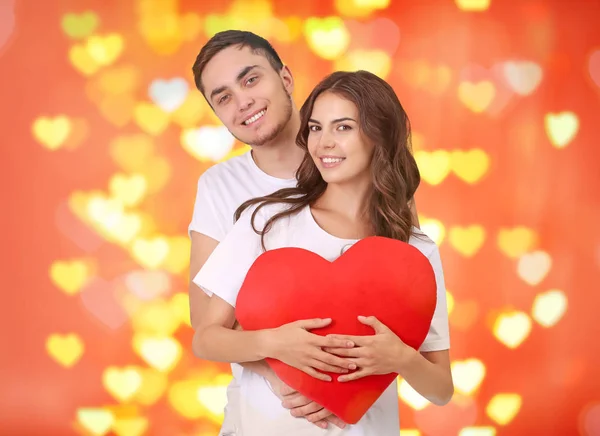 Casal jovem com coração posando no fundo embaçado — Fotografia de Stock