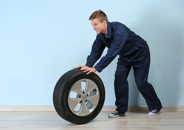 Young mechanic in uniform with wheel — Stock Photo, Image