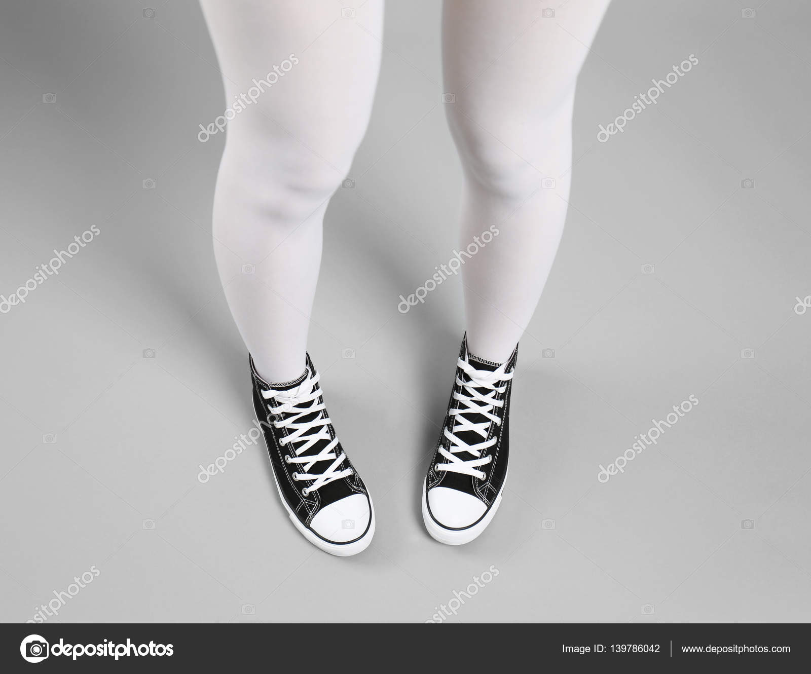 Woman in white tights and sneakers on gray background Stock