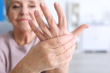 Elderly woman suffering from pain in hand, closeup clipart