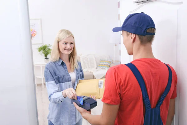 Junge Frau bezahlt Paket vom Kurier — Stockfoto