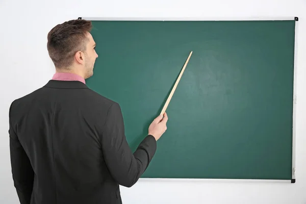 Jonge mannelijke leraar naast blackboard — Stockfoto